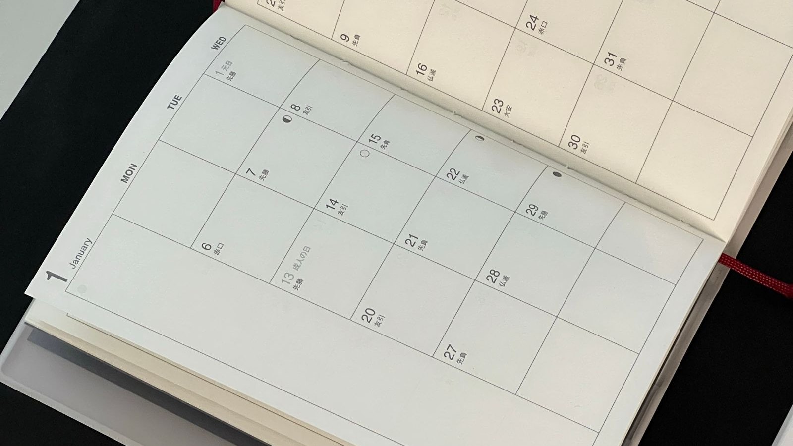 Agenda de papel aberta ao lado de caneta