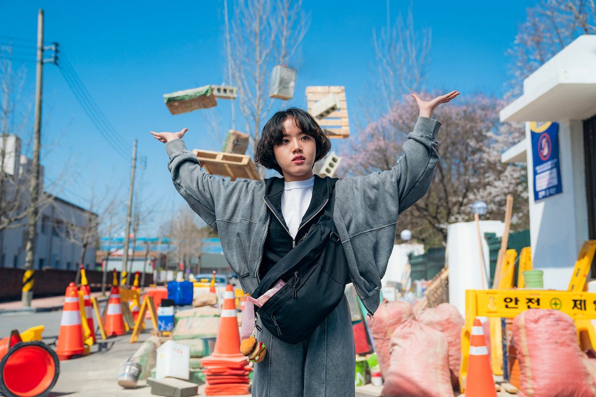Kim Hyang-gi como Bang Eun-mi de braços erguidos numa obra enquanto tijolos flutuam no ar ao redor dela