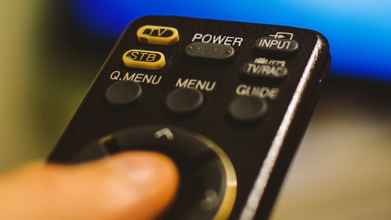 Controle remoto em primeiro plano diante de uma televisão