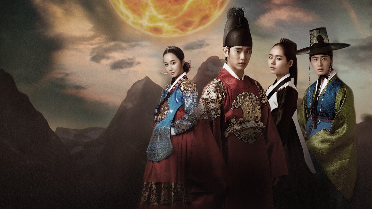 Quatro atores em trajes da era Joseon diante de montanhas escuras sob um grande sol alaranjado