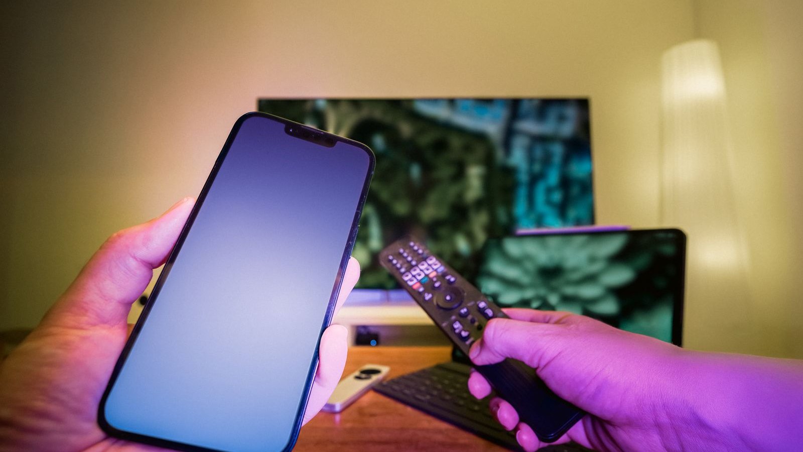 Controle e telefone diante de televisão desfocada