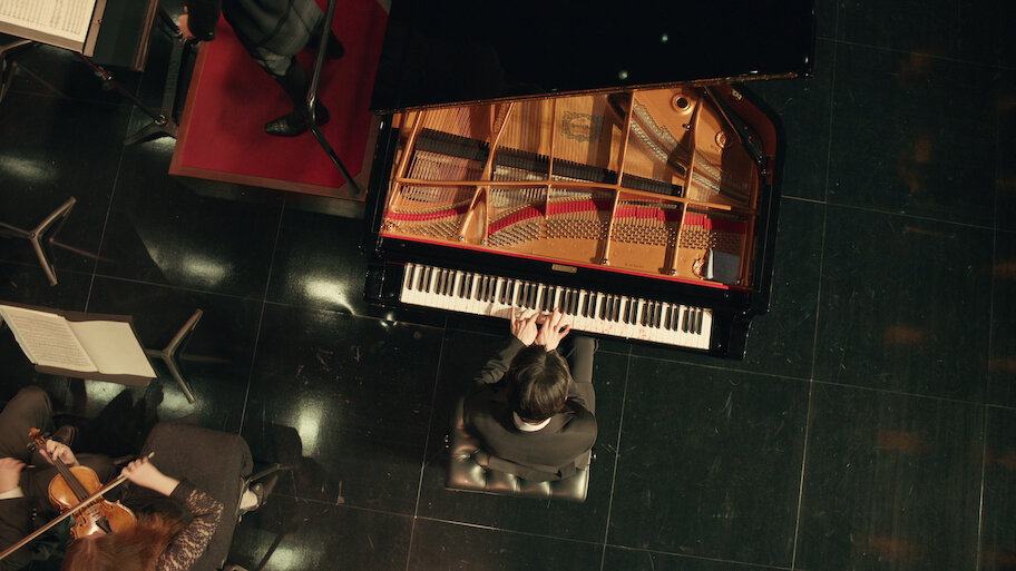 Pianista ao teclado visto de cima em cena promocional de Quatro Mãos, Duas Sonatas